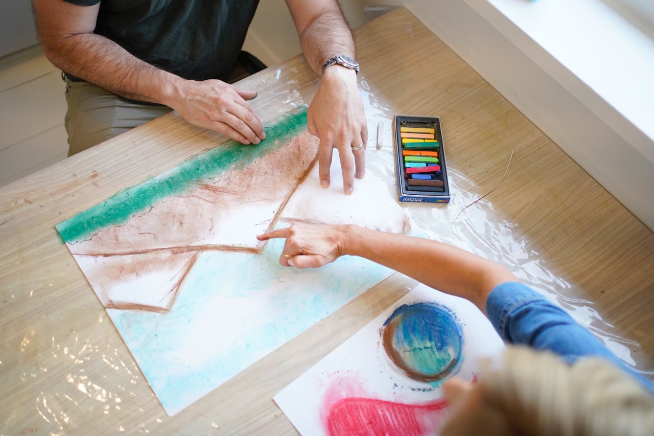 Hands painting together at the studio table