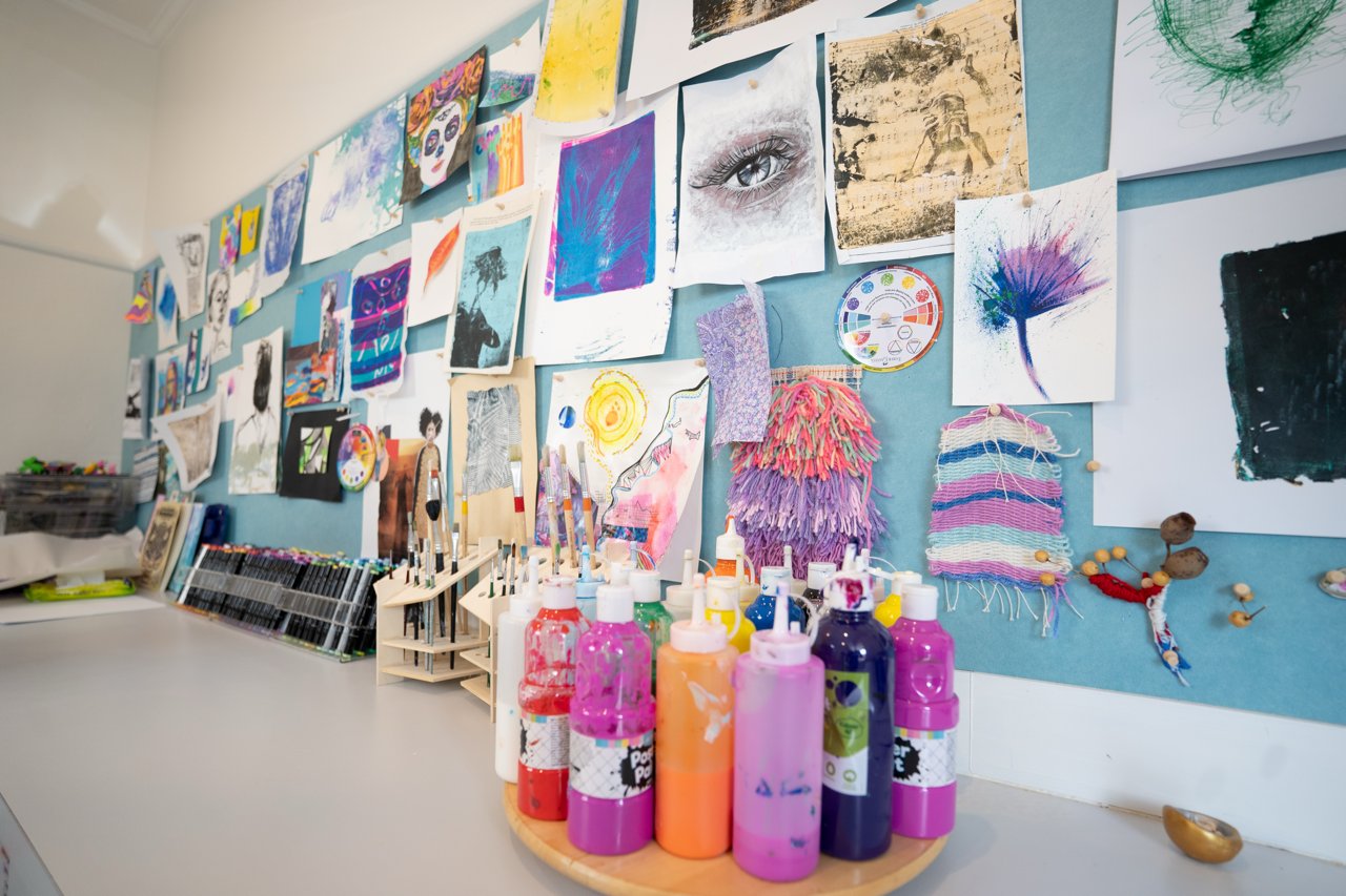 Paint bottles in front of the studio artwork wall